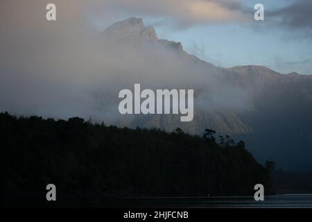 Petrohue, Los Lagos, Chile. 29th Januar 2022. Nebel bedeckt die Berge bei Sonnenaufgang am Todos Los Santos See in Petrohue, Südchile. (Bild: © Matias Basualdo/ZUMA Press Wire) Stockfoto