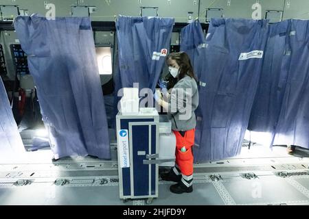 Calden, Deutschland. 29th Januar 2022. Helfer und medizinisches Personal stehen in einem Airbus A400 M der deutschen Luftwaffe, der sich auf dem Asphalt des Flughafens Kassel befindet, während einer Impfkampagne zur Eindämmung des Coronavirus. Die Impfaktion im Airbus ist eine Kooperation zwischen dem Flughafen Kassel, dem Johanniter Regionalverband Kurhessen und dem Lufttransportgeschwader 62 aus Wunstorf. Quelle: Swen Pförtner/dpa/Alamy Live News Stockfoto