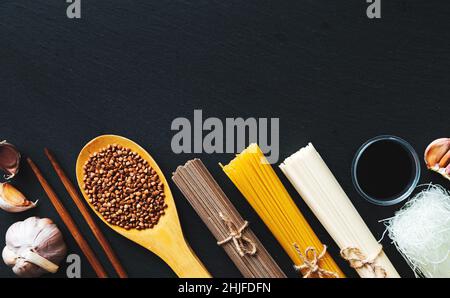 Nudeln aus verschiedenen Ländern. Soba, udon, Spaghetti, funchose. Schwarzer Hintergrund, flaches Lay, Kopierbereich. Hintergrund der Speisen. Stockfoto