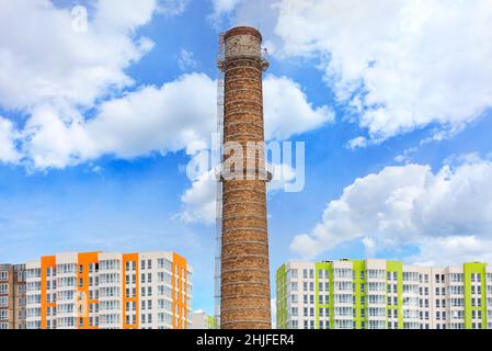 Vor dem Hintergrund erhebt sich der Backsteinkamin des Wärmekraftwerks über den im Bau befindlichen neuen Häusern im Schlafbereich der Stadt Stockfoto