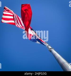 Eine amerikanische Flagge und eine texanische Staatsflagge fliegen im Wind von einem Fahnenmast in El Paso, Texas. Stockfoto