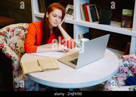 Freiberufliche Mitarbeiterin, die in der Cafeteria an einem Laptop mit Notebook arbeitet Stockfoto
