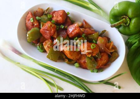 Idli Manchurian. Ein indochinesisches Fusionsküche, das mit übrig gebliebenen Idlis, Paprika und Frühlingszwiebeln hergestellt wird. Vorbereitet durch Schneiden von übrig gebliebenen Idlis in kleine Müllcontainer Stockfoto