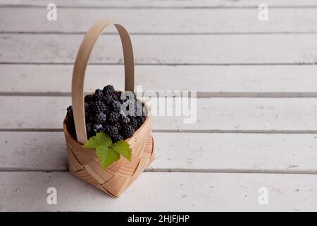 Frische Brombeeren in einem Korb. Sommer Bio-Beeren auf weißem Holz Hintergrund Stockfoto