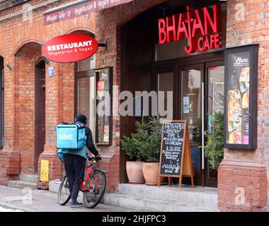 Krakau. Krakau. Polen. Food Delivery Courier parkt sein Fahrrad vor dem 'Bhajan Cafe', einem vegetarischen und veganen indischen Restaurant. Stockfoto