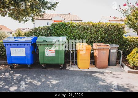 Krk, Kroatien - 24. August 2021: Mülltrennbehälter auf der Straße auf der Insel Krk, Kroatien. Sortieren von organischen, metallischen, Papier- und Kunststoffabfällen Stockfoto