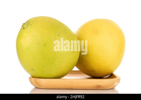 Zwei saftige süße Pomelos auf einem Holztablett, Makro, isoliert auf Weiß. Stockfoto