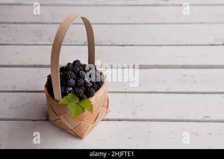 Frische Brombeeren in einem Korb. Sommer Bio-Beeren auf weißem Holz Hintergrund Stockfoto