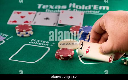 Hände eines Mannes, der ein Paar Asse und Pokerchips zeigt. Stockfoto