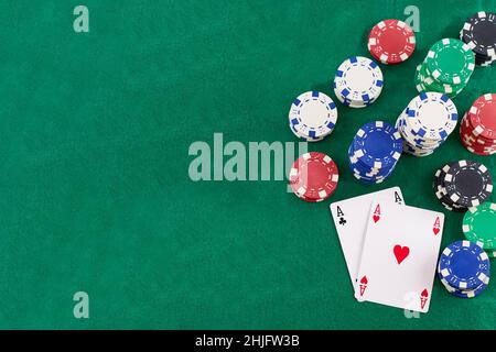 Paar Asse und Pokerchips auf grünem Hintergrund, mit Platz zum Kopieren. Stockfoto