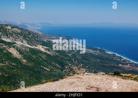 Luftaufnahme des schönen Sommerresorts – ruhiges blaues Meerwasser und Berge mit grünem Gras bedeckt. Albaniens Landschaft. Stockfoto