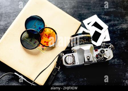 Vintage-Kamera, Filter und Diapositive von oben in einem dunklen Holztisch. Stockfoto