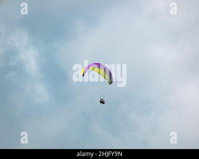 Belmira, Antioquia, Kolumbien - November 20 2021: Gelbes und violettes Gleitschirmfliegen, Extremsport am Morgen mit wolkenbedecktem Hintergrund Stockfoto