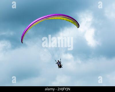 Belmira, Antioquia, Kolumbien - November 20 2021: Gelbes und violettes Gleitschirmfliegen, Extremsport am Morgen mit wolkenbedecktem Hintergrund Stockfoto