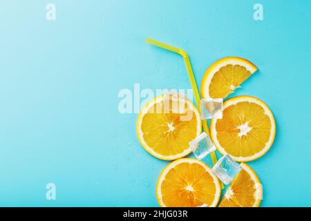 Orangenscheiben und Eiswürfel mit einem Strohhalm auf blauem Hintergrund in Form eines Cocktails. Das Konzept der Limonade ist eine sommerliche Erfrischung Stockfoto