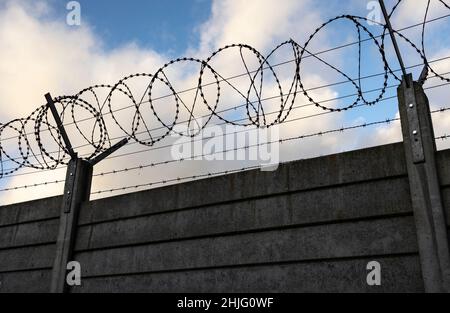 Silhouette aus Sicherheitsrasierdraht und Stacheldraht auf einer Tafelwand blauer Himmel und Wolken Stockfoto