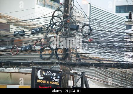 PHUKET, THAILAND - 13. MÄRZ 2018. Lampenpfosten auf Gewirr von elektrischen Drähten Hintergrund. Redaktionelle Tagesaufnahme Stockfoto