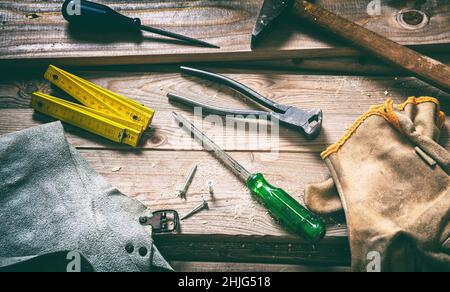 Handwerkzeug alten Hammer Schraubendreher und Handschuh auf Holz, Schreinerei Vintage-Ausrüstung. Arbeitswerkzeug auf Holzhintergrund verwendet. Bauindustrie Stockfoto