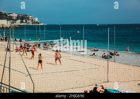 NIZZA, FRANKREICH - 26. JUNI 2017: Menschen, die am Steinstrand sonniges Wetter genießen und Beachvolleyball spielen in Nizza, in der Nähe der Promenade des Anglais, F Stockfoto