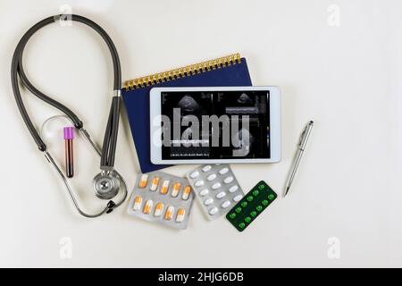 Medizinischer Arbeitstisch Arzttisch mit SCI FI Heads up Herzbericht Analyse der Patientenanzeige Sprachdruck in digitalen Tablet-PC Stockfoto