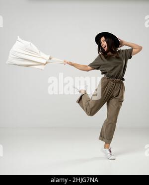 Zero Waste Konzept. Glückliche junge Brünette Frau in einem grünen T-Shirt und schwarzem Hut tanzen mit einer Baumwolltasche mit Lebensmitteln. Umweltfreundlicher Lebensstil Stockfoto