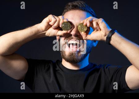 Verrückte glücklich Bitcoin Liebhaber mit goldenen Münze von Augen. Digitales Symbol einer neuen virtuellen Währung. Kryptowährung. Stockfoto