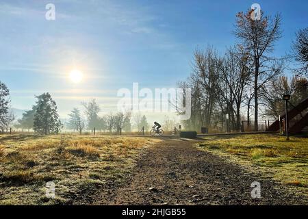 Fahrradfahrer auf dem Boise Greenbelt in der Nähe des Warm Springs Golfplatzes am nebligen späten Herbstmorgen. Stockfoto