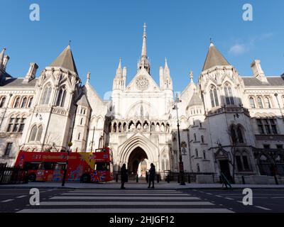 Oben offener Sightseeing-Bus vor den Royal Courts of Justice am Strand, während Fußgänger auf einer Fußgängerüberführung stehen. London. Stockfoto