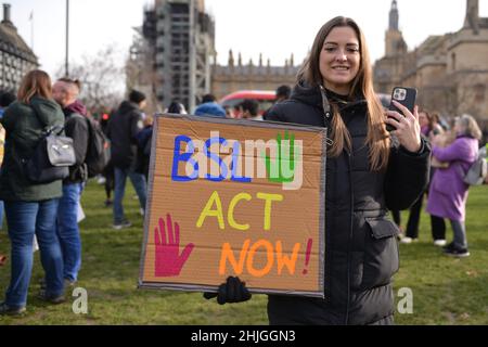 Eine Protesterin sah, wie sie während der Demonstration ein Plakat mit ihrer Meinung hielt. Britische Gebärdensprache und gehörlose Gemeinschaft versammelten sich gegenüber dem britischen Parlament zur Unterstützung des BSL-Gesetzes (British Sign Language), das die Gebärdensprache als Amtssprache des Vereinigten Königreichs anerkennt. Stockfoto