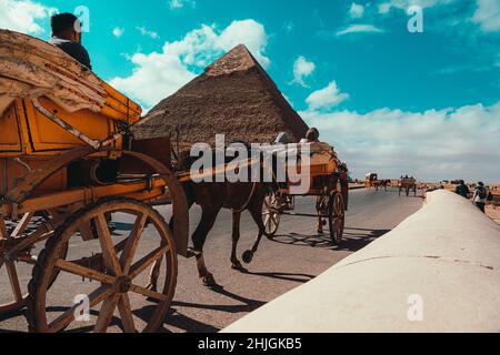 Kairo Ägypten Dezember 2021 Rückansicht eines Pferdewagens, der um die großen Pyramiden von gizeh reitet. Für Touristen ist die Gegend sehr beliebt Stockfoto