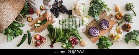 Herbst vegetarische Küche Hintergrund. Weibliche Hände schneiden Gurken auf dem Tisch mit frischem Gemüse der Saison, Gemüse, Obst vom lokalen Lebensmittelmarkt, zu Stockfoto