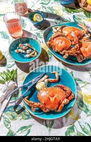 Gekochte Krabben, lemos, Rosenwein auf dem Tisch, Sonneneinstrahlung. Stockfoto