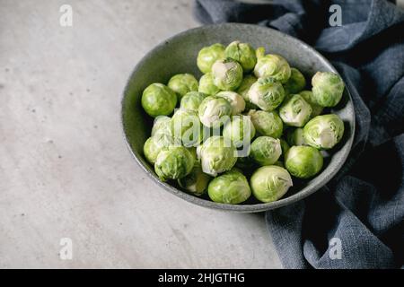 Haufen von geschälten rohen Bio-rosenkohl Mini-Kohl in Keramikschale auf hellgrauem Hintergrund. Gemüse gesund essen. Speicherplatz kopieren Stockfoto