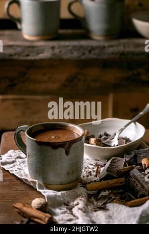 Tasse heiße würzige hausgemachte Schokolade Winter Drink mit gehackter dunkler Schokolade und Zutaten auf rustikalen Leinentischtuch. Landküche Tisch. Warm c Stockfoto