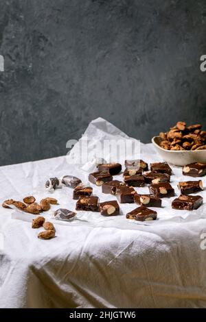 Hausgemachtes Toffee, gesalzene Karamell-Schokolade, Mandelkerne auf zerknittertem Papier über weißer Tischdecke. Handgemachte Lebensmittel süße Geschenke für jeden Urlaub. Stockfoto