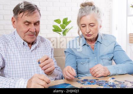 Seniorenpaar, das zu Hause an einem Puzzle arbeitet Stockfoto