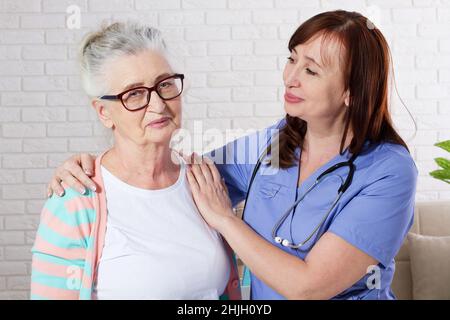 Glückliche ältere Frau mit Krankenschwester in einer Physiotherapie. Stockfoto