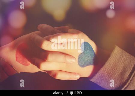 Nahaufnahme von zwei bemalten Händen, die halten, in blauen und roten Farben. Stockfoto