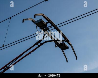 Pantograph eines Zuges, der auf einer elektrischen Linie auf blauem Himmel-Hintergrund verbindet Stockfoto