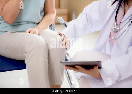 Nahaufnahme der Hände einer Ärztin, die einen Tablet-Computer hält, und ermutigen den Patienten im Krankenhaus, in Innenräumen, zwei Personen, Pflegepersonal und ältere Menschen mit Kranken, Stockfoto