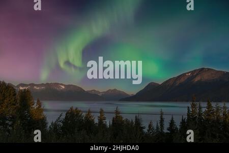 Die Nordlichter, die am Himmel über einem wunderschönen See bei Sonnenuntergang in den Chugach Mountains in Alaska leuchten Stockfoto