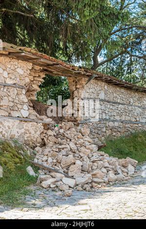 Teilweise zerstörte Wand Teil des Steinzauns eines Hauses in einem bulgarischen Dorf. Stockfoto