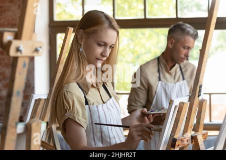 Junge Handwerk Studio-Klasse Schüler in Schürze Zeichnung in Farben Stockfoto