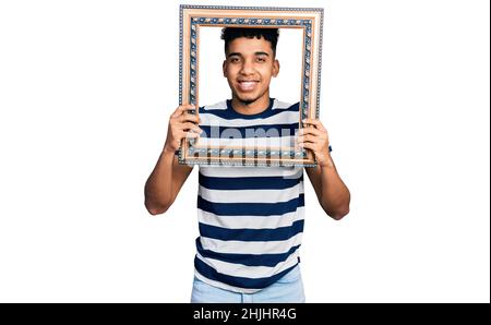 Junger afroamerikanischer Mann mit leerem Rahmen lächelnd und laut lachend, weil witziger verrückter Witz. Stockfoto