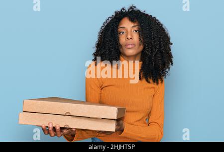 Junge afroamerikanische Mädchen hält Lieferung Pizza Box Denken Haltung und nüchternen Ausdruck selbstbewusst suchen Stockfoto
