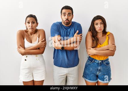 Eine Gruppe junger hispanischer Menschen, die wegen der Winterkälte über einem isolierten Hintergrund stehen und zittern, mit trauriger und schockierender Gesichtsausdruck Stockfoto