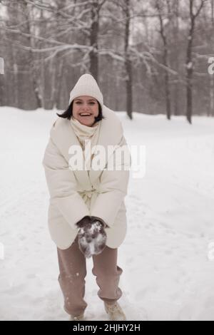 Zwei Mädchen spielen im Winter Schneebälle im Schnee in einer warmen Winterkleidung Stockfoto