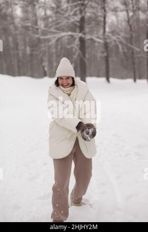 Zwei Mädchen spielen im Winter Schneebälle im Schnee in einer warmen Winterkleidung Stockfoto