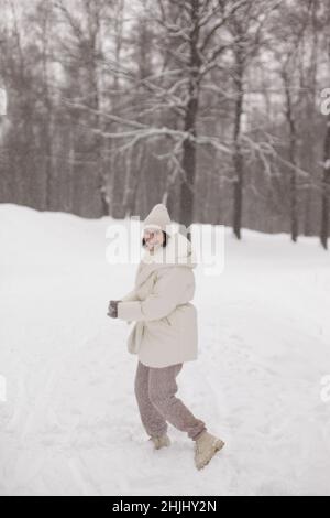 Zwei Mädchen spielen im Winter Schneebälle im Schnee in einer warmen Winterkleidung Stockfoto