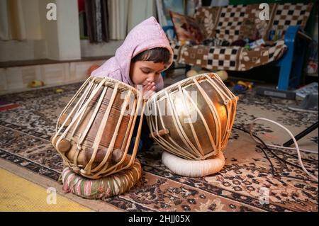 Ein kleines Kind versucht zu lernen, die Tabla zu spielen. Stockfoto